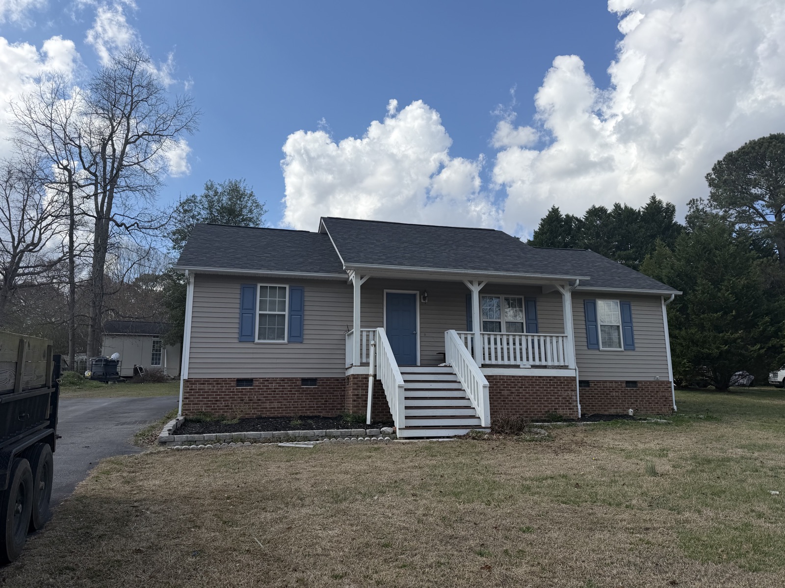 The same ranch home with its new dark shingle roof completed