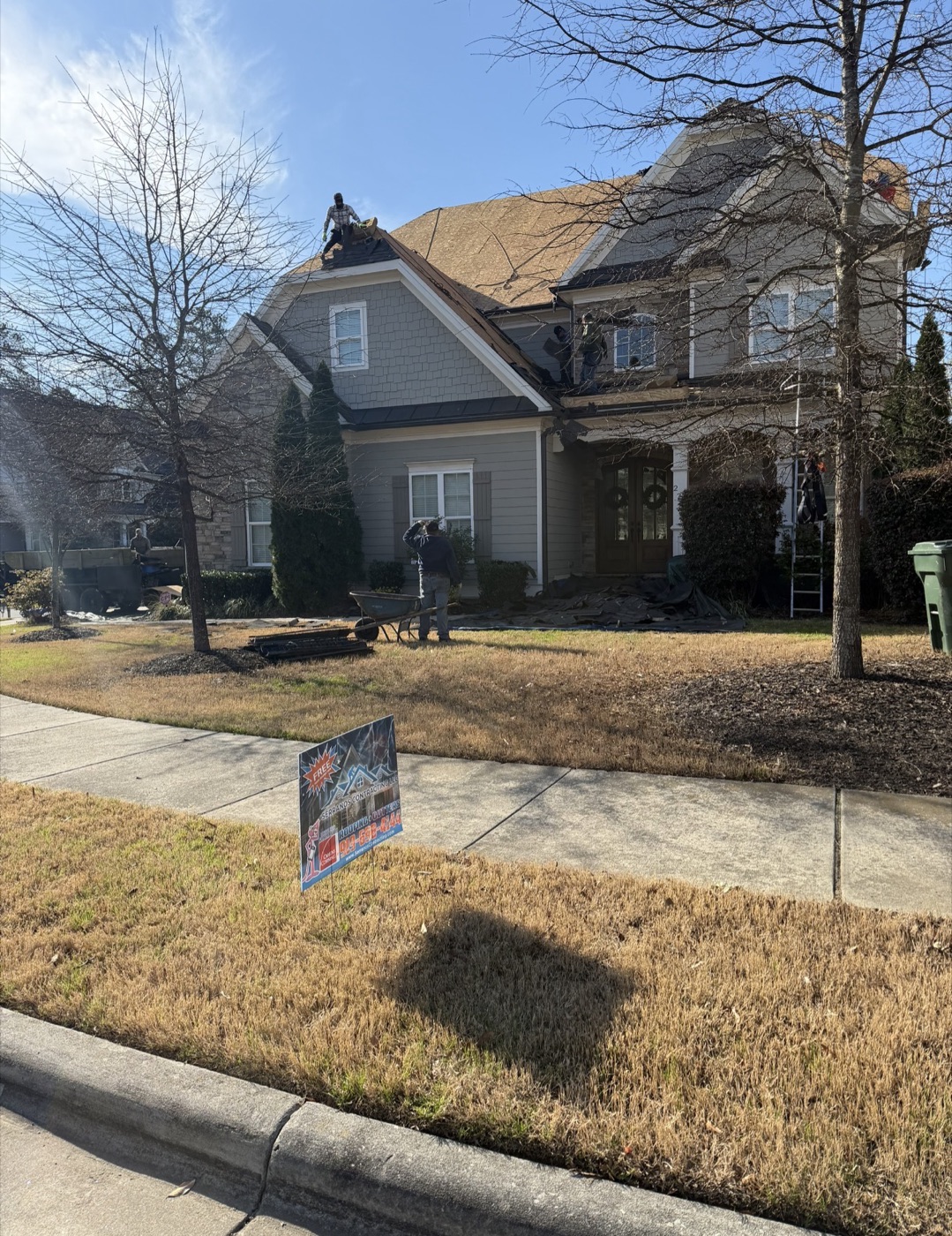 Serranos Contracting yard sign in front of a roof replacement in progress, tarps protecting the home